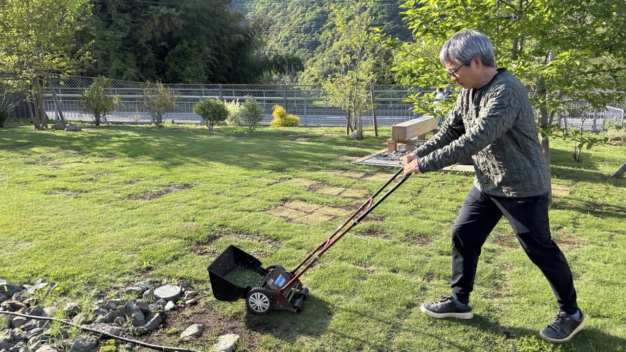 手押し芝刈り機で草刈りする男性